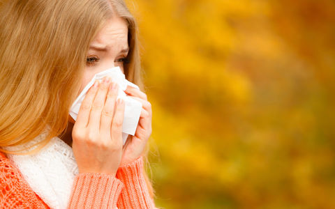 Bilde av en dame med langt hår som snyter seg med papirlommetørkle.